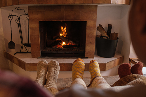 Family's socked feet in front of fireplace cared for by Manahawkin chimney service